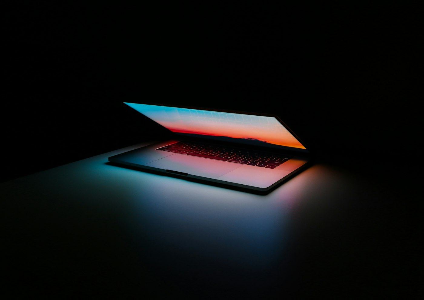 Laptop open in a dim room, the kind of desk where work actually happens